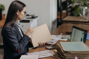 Professional woman reviewing financial documents and spreadsheets at an office desk.