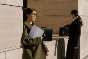 Two business professionals carrying documents and briefcases outside a modern office building.