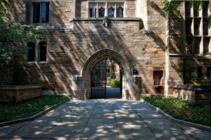 Historic university building featuring a Gothic stone archway and landscaped courtyard.